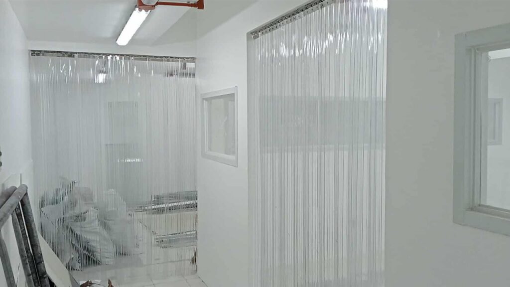 Clear PVC strip curtains mounted on metal rails across clean indoor doorways